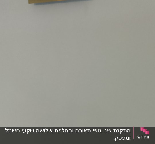 מנורת קיר זהובה ושקע חשמל על קיר